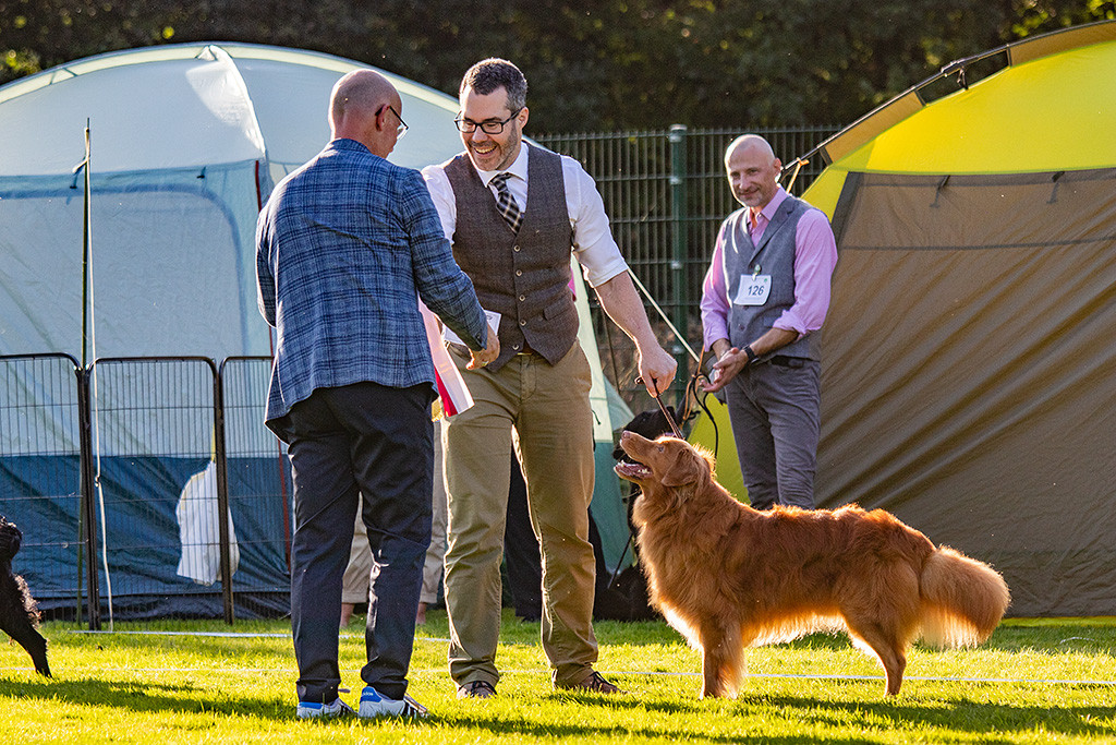 Der Richter übergibt Stephan gratulierend die Best Veteran in Show Schleife, Edison schaut dabei lächelnd hoch