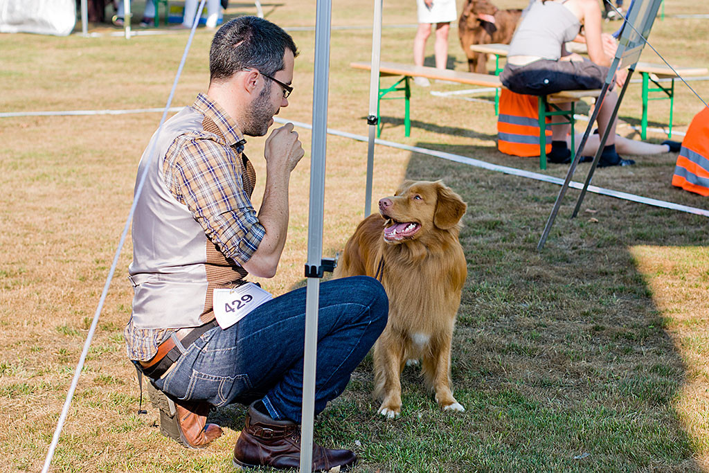 Edison steht im Schatten unter dem Pavillon und lächelt dabei Stephan an, der vor ihm hockt