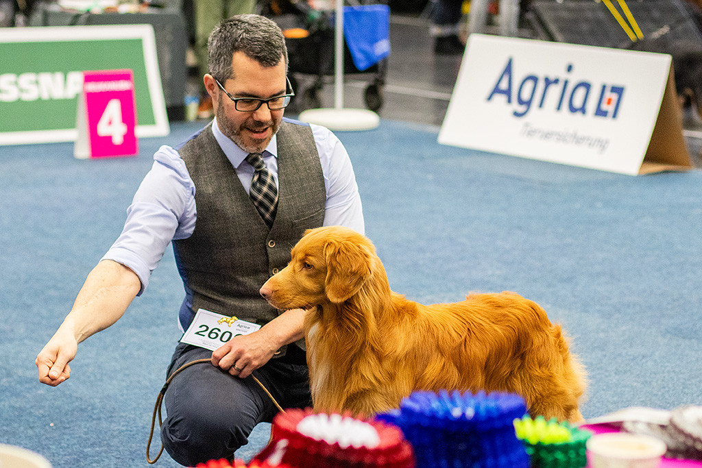 Newton steht beim Richtertisch, Stephan kniet neben ihm und streckt den Arm aus, zu dem er fokussiert hinschaut